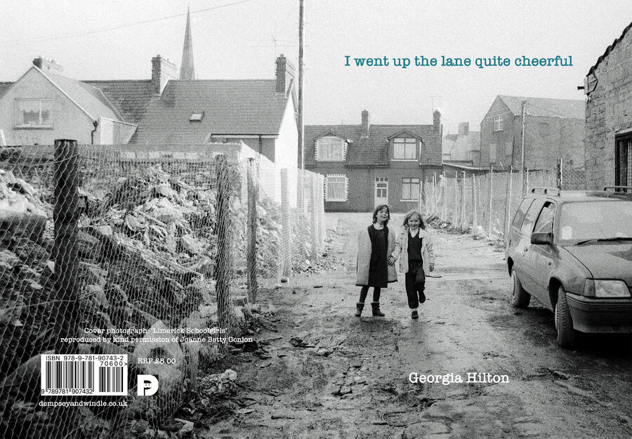 Book cover of poetry pamphlet showing two young primary school girls walking up a muddy street in the early 1990s with houses in the background and rubble behind fencing to their left.