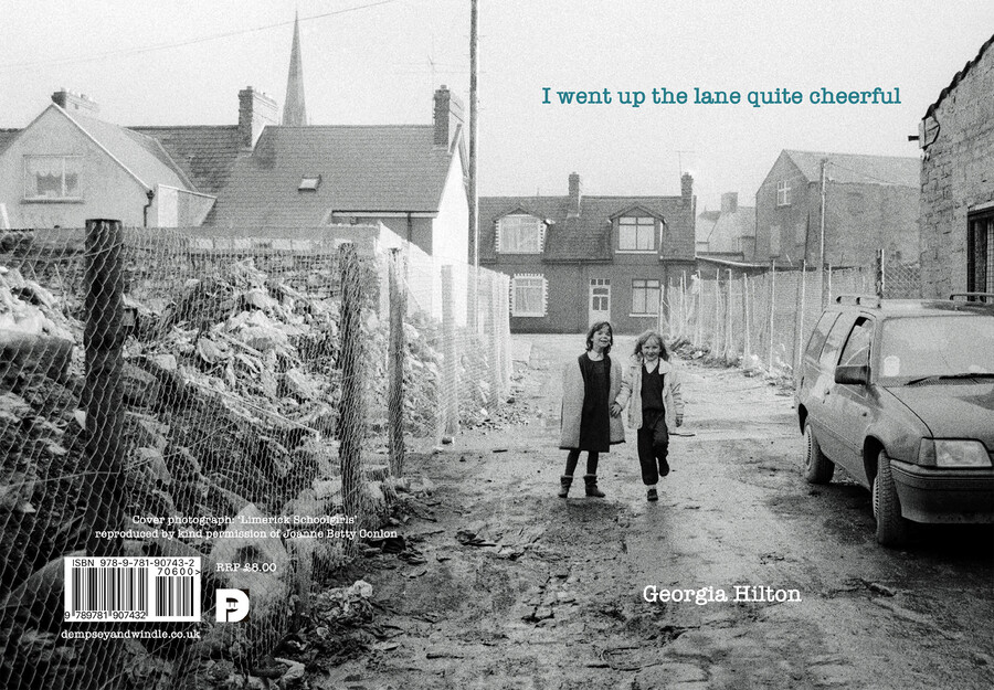 Book cover of poetry pamphlet showing two young primary school girls walking up a muddy street in the early 1990s with houses in the background and rubble behind fencing to their left.